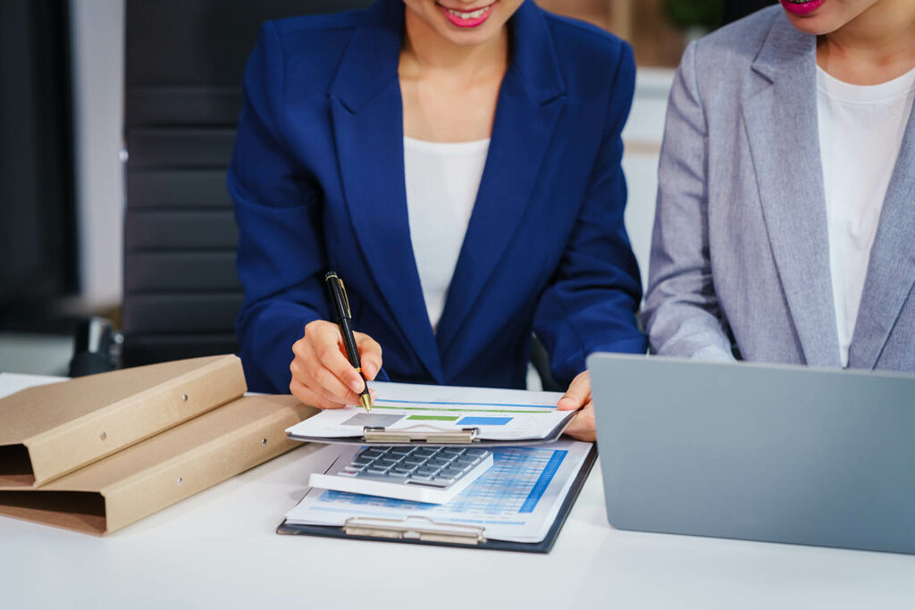 Two Asian businesswomen collaborate on stock market strategies a